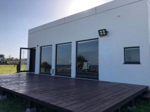 a white house with a wooden deck and windows at ゴールデンマイルヴィラ in Amami