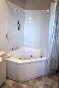 a white bath tub in a white tiled bathroom at Baywatch Motor Lodge in Timaru +45 photos