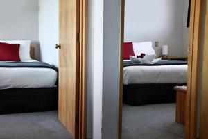 1 dormitorio con 2 camas y almohadas rojas y blancas en Baywatch Motor Lodge, en Timaru