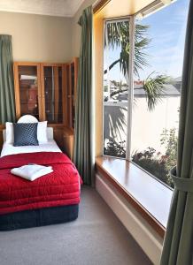 a bedroom with a red bed and a large window at Baywatch Motor Lodge in Timaru