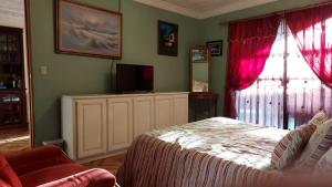 a bedroom with a bed with red curtains and a television at Alexander b&b in Alajuela City