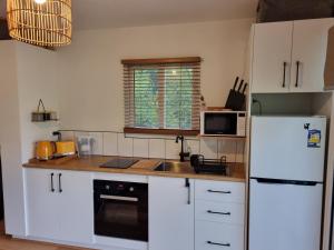 a kitchen with white cabinets and a white refrigerator at Cozy Otways Accommodation in Beech Forest