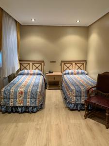 a hotel room with two beds and a chair at Hotel Julia in Aranda de Duero