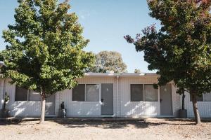 a house with two garage doors and two trees at Cedar Lodge in Braidwood