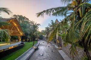 a view of the resort with a bench and palm trees at Harsono Boutique Resort Bali in Sanur