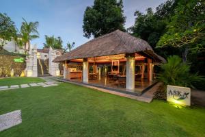 a restaurant with a thatched roof in a yard at Harsono Boutique Resort Bali in Gianyar