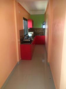 una pequeña cocina con armarios rojos y paredes verdes en Malar inn, en Port Blair