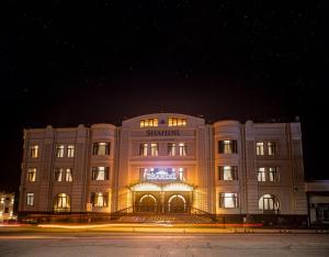 Un grand bâtiment est éclairé la nuit. dans l'établissement HOTEL SHAHDIL, à Samarcande