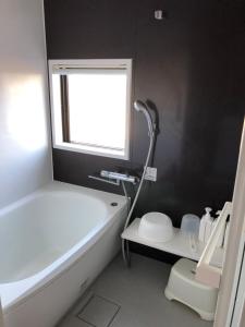 a bathroom with a tub and a toilet and a window at ゴールデンマイルヴィラ in Amami