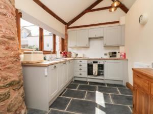 een keuken met witte kasten en een tegelvloer bij Middle Burrow Cottage in Minehead
