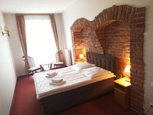 Cama en habitación con pared de ladrillo en Hotel Bartis en Bartoszyce