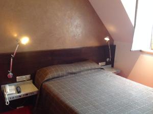 a bedroom with a bed and two lights on the wall at Hôtel La Gibecière in Lohéac