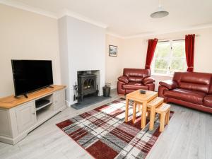 a living room with a tv and a couch and a table at Glyn Cottage in Llanon
