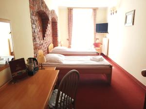 Zimmer mit 2 Betten und einem Schreibtisch mit Tisch in der Unterkunft Hotel Bartis in Bartoszyce