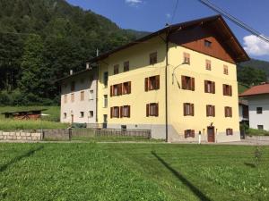 un grande edificio giallo con un prato davanti di Penasa Appartamenti a Rabbi