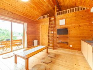 Pokój z drewnianą ścianą ze stołem i telewizorem w obiekcie 石垣島コテージAkeeesi365 w mieście Ishigaki