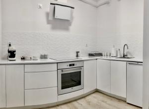 a white kitchen with white cabinets and an oven at Apartament Rzeszów Centrum in Rzeszów