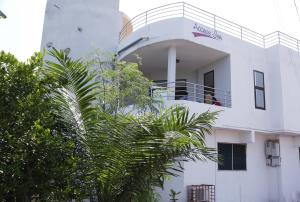 a white building with a balcony and a palm tree at Access Inn in Accra