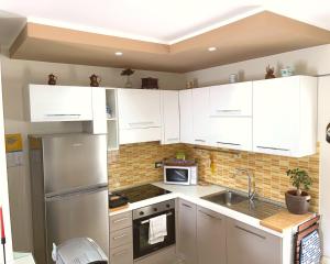 a kitchen with white cabinets and a stainless steel refrigerator at Hermitage - BABsuites in Dogliola