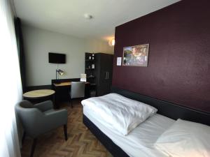 1 dormitorio con cama, silla y escritorio en Akzent City-Hotel Kleve, en Kleve