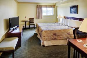 ein Hotelzimmer mit einem großen Bett und einem Schreibtisch in der Unterkunft Nova Inn Edson in Edson
