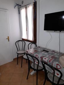 een kamer met een tafel en stoelen en een flatscreen-tv bij Appartamento “Il Borgo” in Peccioli