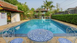 a swimming pool with chairs and a table in front of a house at Chiang Mai Las Orquideas Resort in Chiang Mai