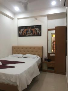 a bedroom with a large bed and a mirror at Purple Lotus Hotel in Varanasi
