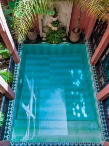 a swimming pool with a statue of a woman and a cross at Riad Aderbaz in Marrakech