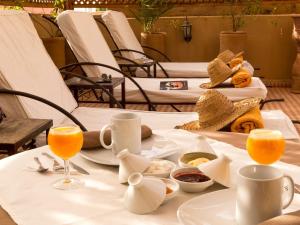 una mesa con un plato de comida y vasos de zumo de naranja en Riad Aderbaz, en Marrakech