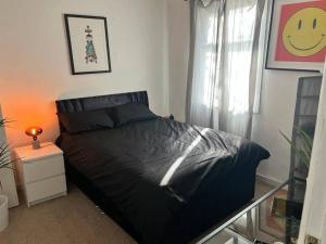 a bedroom with a bed with a black comforter and a window at Spacious 3 bedroom house close to city centre in Bristol