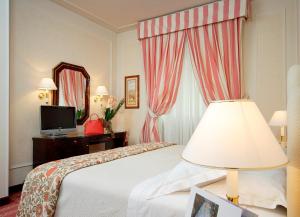 una camera d'albergo con letto, lampada e specchio di Hotel De La Ville a Firenze