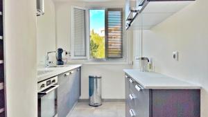 una cucina bianca con lavandino e finestra di LA LANTERNE a Nizza Altre 24 foto