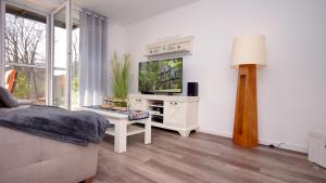 uma sala de estar branca com uma televisão e um sofá em Ferienwohnung Lieblingsplatz em Ostseebad Sellin