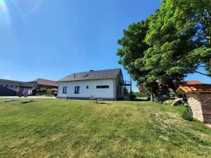 ein weißes Haus mit einem Baum und einem Grasfeld in der Unterkunft Ferienwohnung "Auszeit" Objekt-ID 131789 in Waren (Müritz)