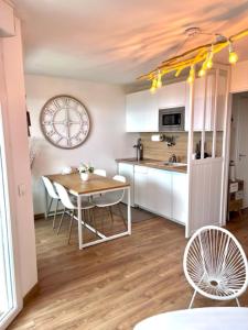 een keuken met een tafel en stoelen en een klok bij VILLA LES PLANCHES DEAUVILLE PLAGE CASINO in Tourgeville