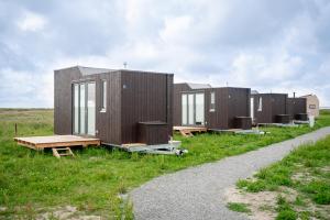 a row of modular houses in a field at Tiny House Nature 3 Zur Kuhweide - Green Tiny Village Harlesiel in Carolinensiel