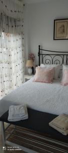 サン・ルイス・デ・サビニリャスにあるApartamento Turístico FlorHouseのベッドルーム1室(白いシーツとピンクの枕が備わる大型ベッド1台付)