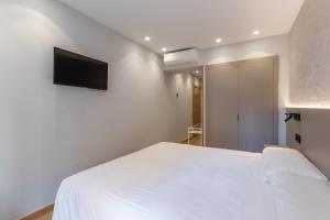 1 dormitorio con 1 cama blanca y TV de pantalla plana en EightRooms La Rioja Pension, en Logroño