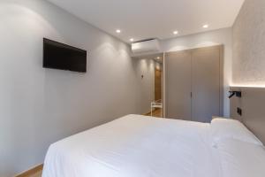 a bedroom with a white bed and a flat screen tv at EightRooms La Rioja Pension in Logroño