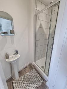 uma casa de banho branca com um chuveiro e um lavatório. em 264 The Hungerford em Crewe
