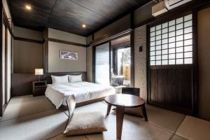 a bedroom with a bed and a table and window at Beppu Nagomitsuki in Beppu