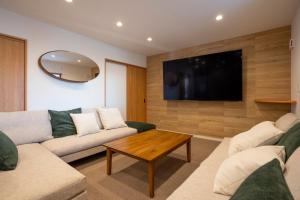 ein Wohnzimmer mit einem Sofa und einem TV in der Unterkunft ASAE in Azagawa