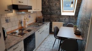 eine Küche mit einer Theke und einem Tisch mit Stühlen in der Unterkunft Gästehaus Zur alten Post - Wohnung West in Dornum