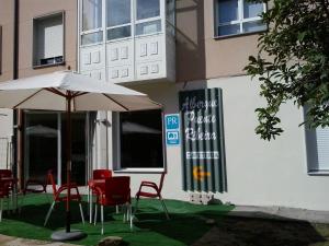 stół z krzesłami i parasol przed budynkiem w obiekcie Pensión-Albergue Puente Ribeira w mieście Sarria