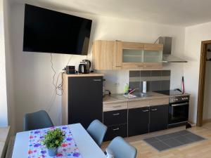 uma pequena cozinha com uma mesa e uma televisão na parede em Ferienwohnung Am Kurpark in Bad Rothenfelde em Bad Rothenfelde