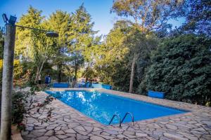 una piscina con un patio de piedra y árboles en Chalés Cantinho da Roça, en Capitólio