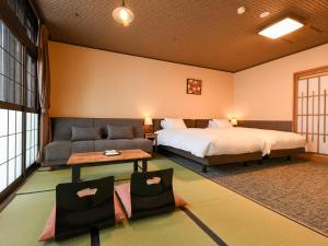 a hotel room with a bed and a couch at Kutsurogijuku Chiyotaki in Aizuwakamatsu