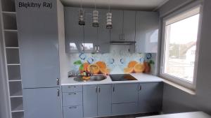 uma cozinha com armários brancos, um lavatório e uma janela em Apartament Błękitny Raj em Krynica Morska