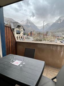 una mesa con copas de vino en un balcón con montañas en Appt hyper-centre Loudenvielle 4pers Terrasse Sud vue montagne en Loudenvielle